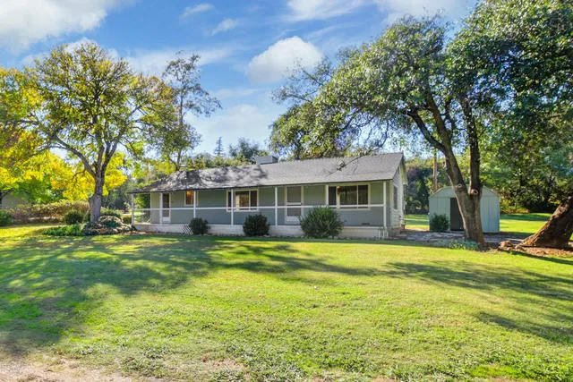 a view of a house with a big yard and large trees