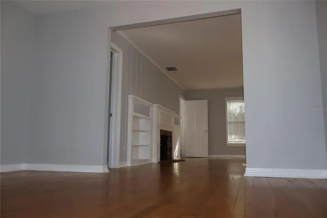 a view of empty room with wooden floor and fan