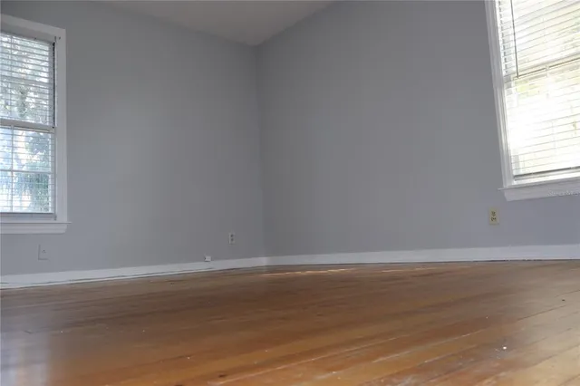 a view of an empty room with wooden floor and closet