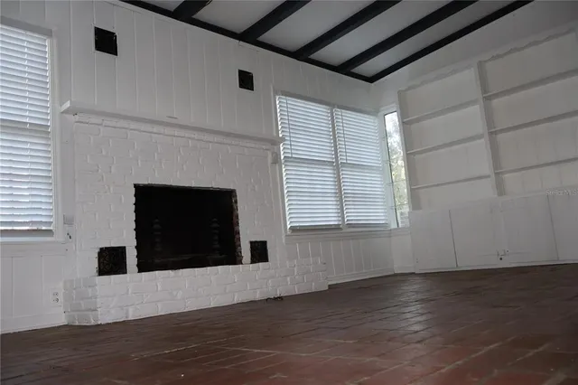 a view of an empty room with wooden floor and a fireplace