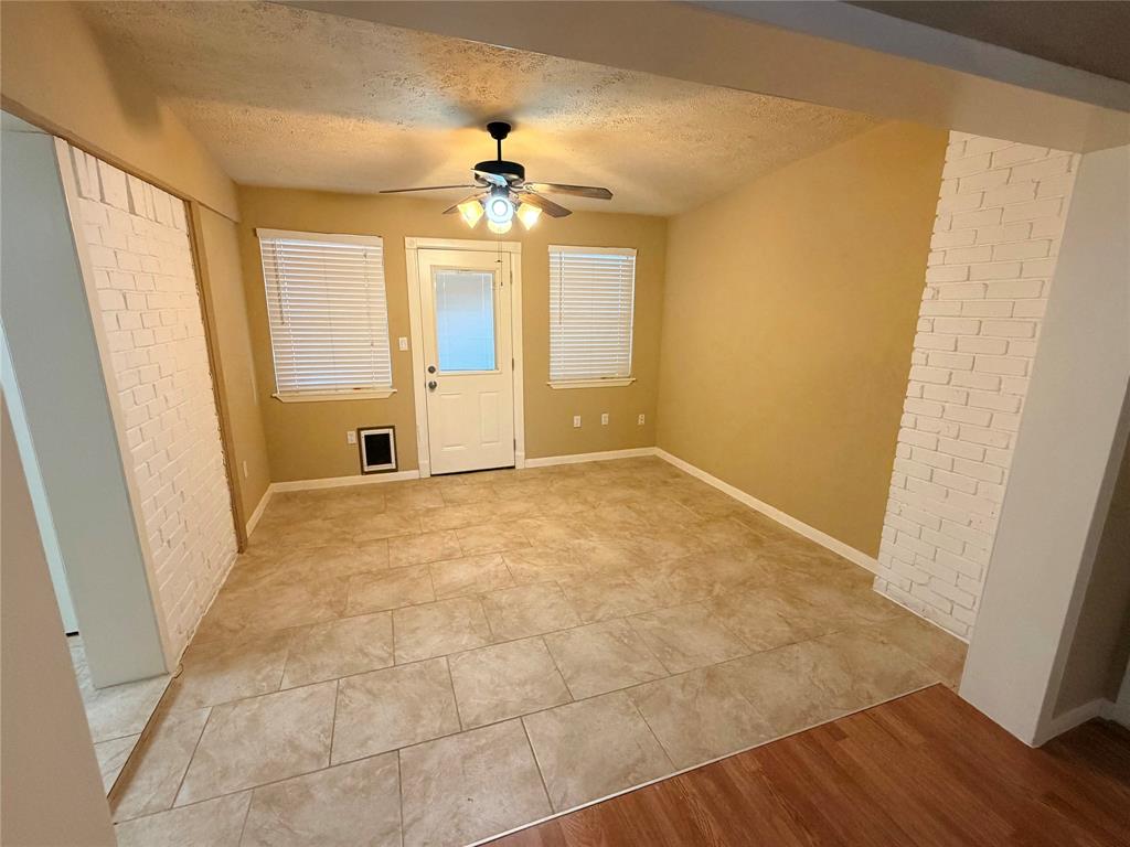2051 Embassy Way Carrollton, TX 75006 - Photo 5 of 20 Entrance foyer with brick wall, a textured ceiling, a ceiling fan, and light tile patterned floors