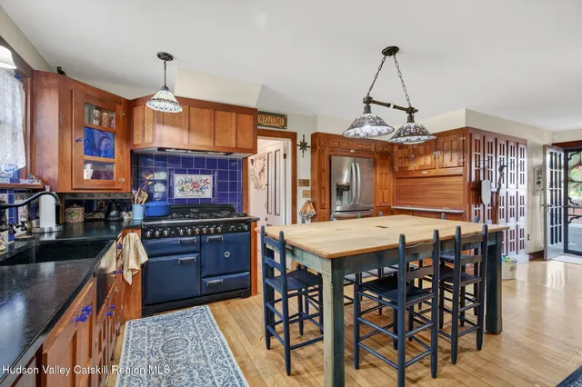 a kitchen with stainless steel appliances granite countertop a stove top oven a sink a dining table and chairs with wooden floor