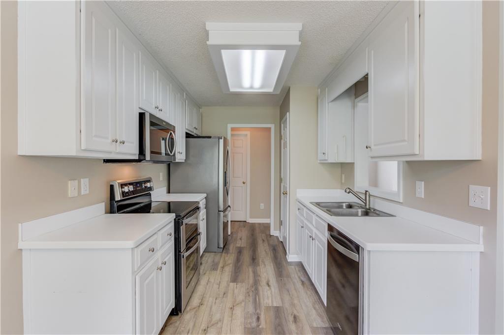 255 Turnberry Lane Winder, GA 30680 - Photo 15 of 41 a kitchen with stainless steel appliances granite countertop a stove top oven a sink dishwasher and a refrigerator with wooden floor