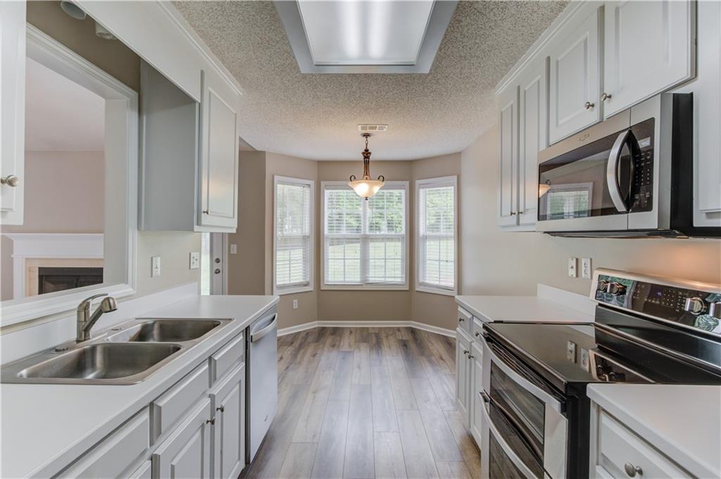 255 Turnberry Lane Winder, GA 30680 - Photo 17 of 41 a kitchen with wooden cabinets a sink and a stove with wooden floor