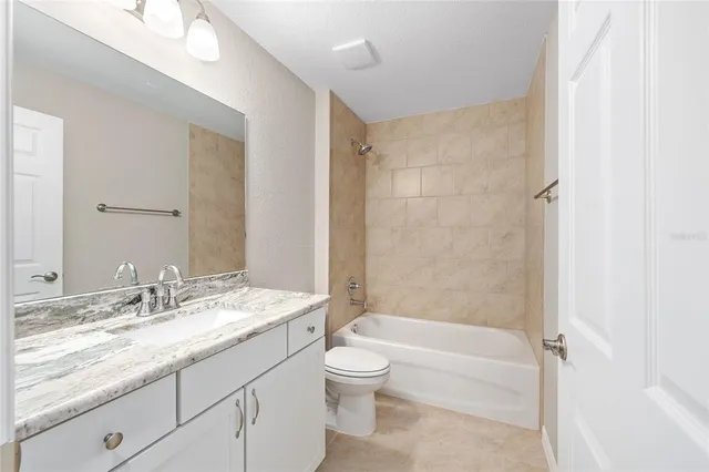a bathroom with a granite countertop sink a toilet and shower