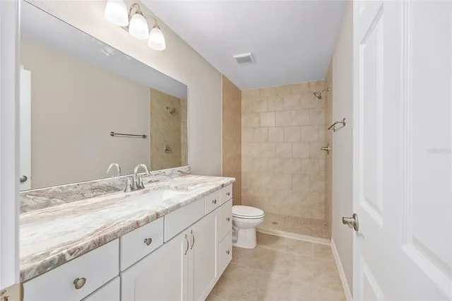 a bathroom with a granite countertop sink toilet and shower