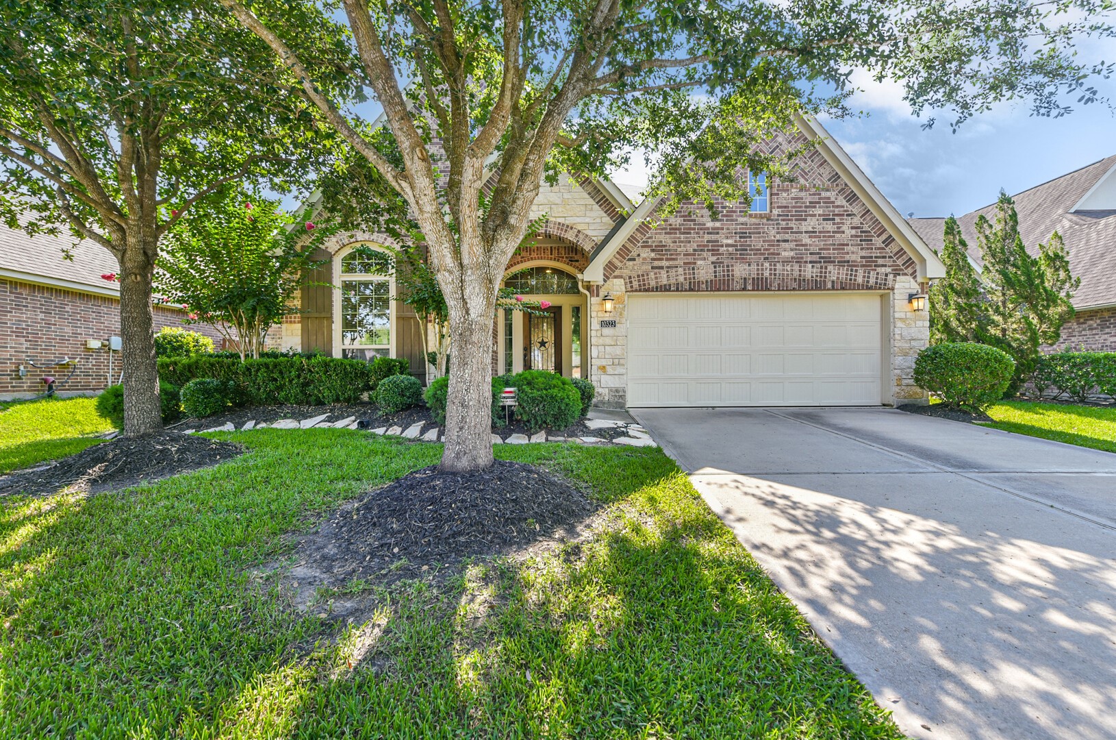 10323 Belvamera Road Richmond, TX 77407 - Photo 2 of 25 Charming brick home, featuring a two-car garage and a well-maintained front yard with mature trees and shrubs for added curb appeal.