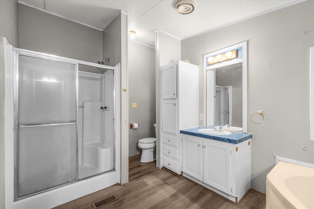1956 North FM 129 Santo, TX 76472 - Photo 12 of 30 Full bathroom with vanity, wood finished laminate floors, a stall shower, crown molding, and a bath