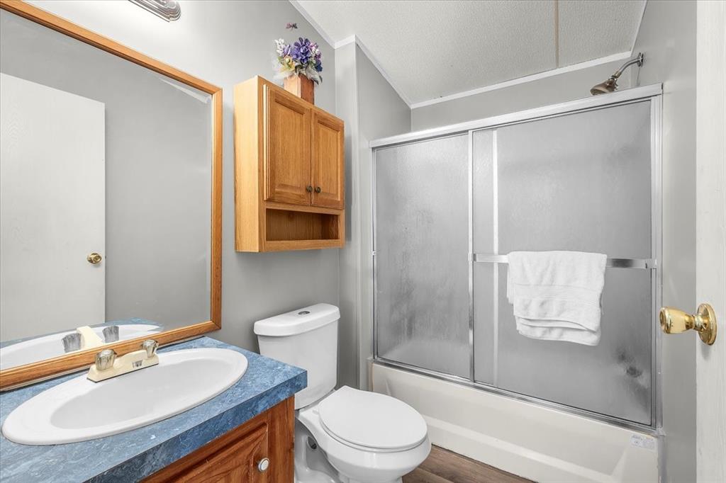 1956 North FM 129 Santo, TX 76472 - Photo 15 of 30 Full bathroom #2 featuring combined bath / shower with glass door, vanity, a textured ceiling, and ornamental molding