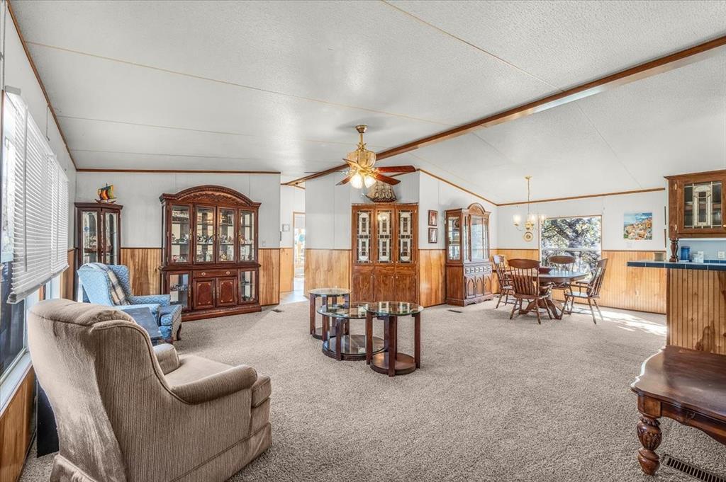 1956 North FM 129 Santo, TX 76472 - Photo 7 of 30 Living room with wainscoting, wooden walls, carpet floors, a chandelier, and a textured ceiling