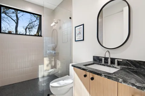 a bathroom with a granite countertop sink a toilet and a mirror