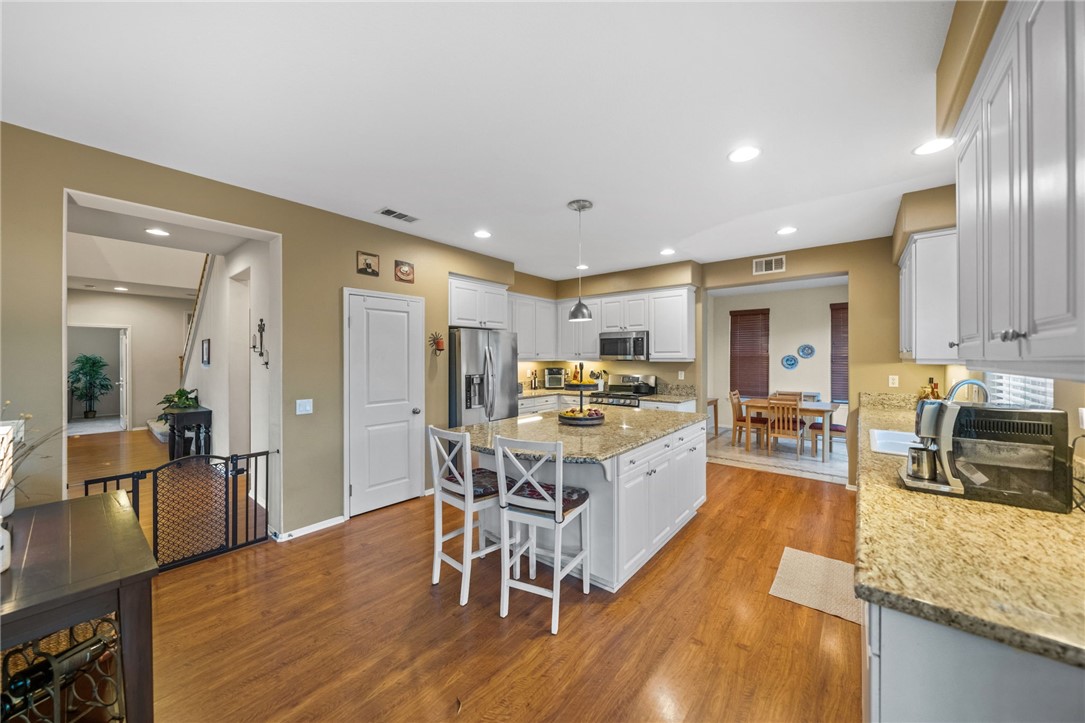 29248 Easton Place Temecula, CA 92591 - Photo 8 of 47 a kitchen with stainless steel appliances granite countertop a refrigerator a stove top oven a sink dishwasher and white cabinets with wooden floor