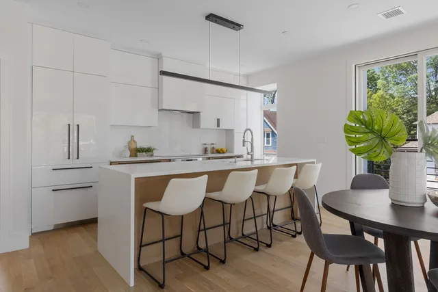 a kitchen with stainless steel appliances a dining table chairs and wooden floor
