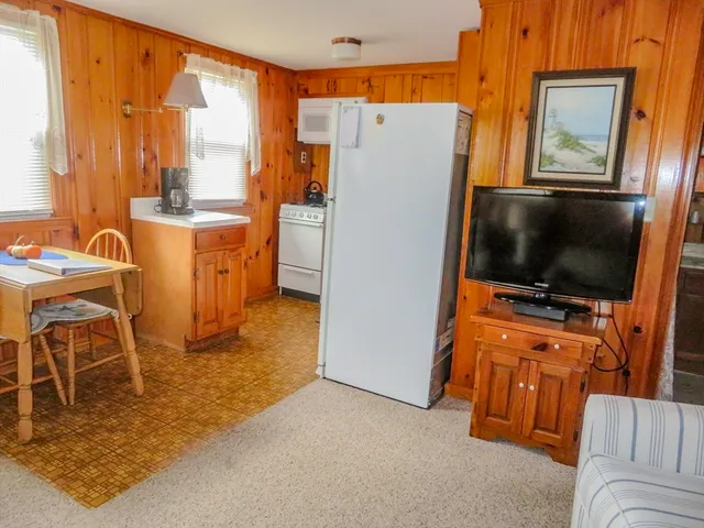 a room with furniture a flat screen tv and a refrigerator