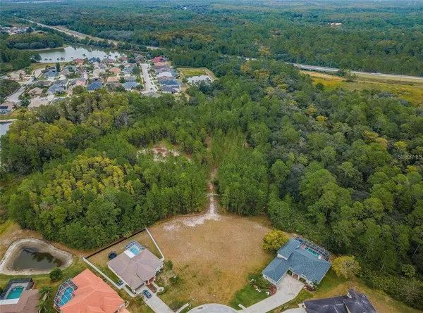 an aerial view of a residential houses with outdoor space and trees