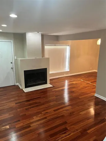 a view of empty room with wooden floor and fireplace