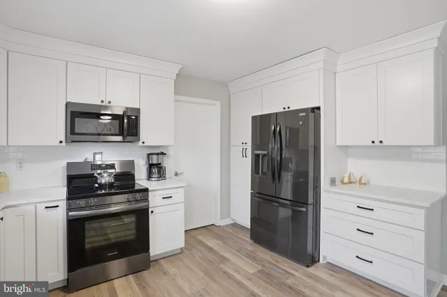 a kitchen with a refrigerator stove and white cabinets
