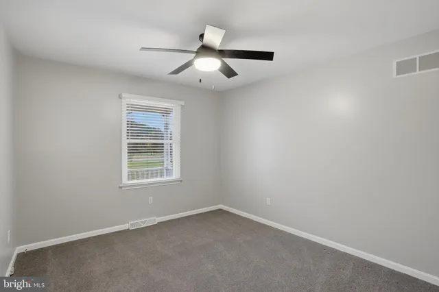 an empty room with a window and ceiling fan