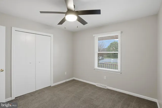 an empty room with a window and a ceiling fan