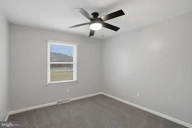 an empty room with window and ceiling fan