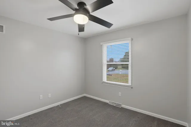 an empty room with a window and a ceiling fan