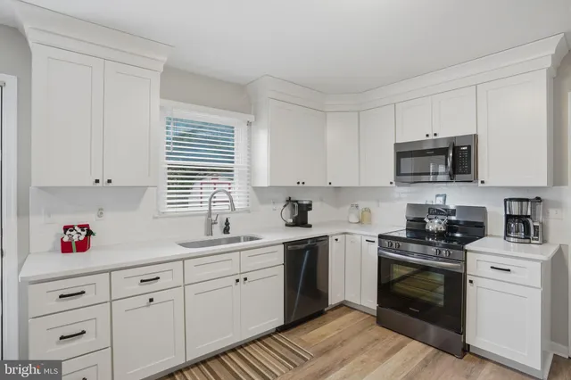 a kitchen with cabinets stainless steel appliances a sink and a window