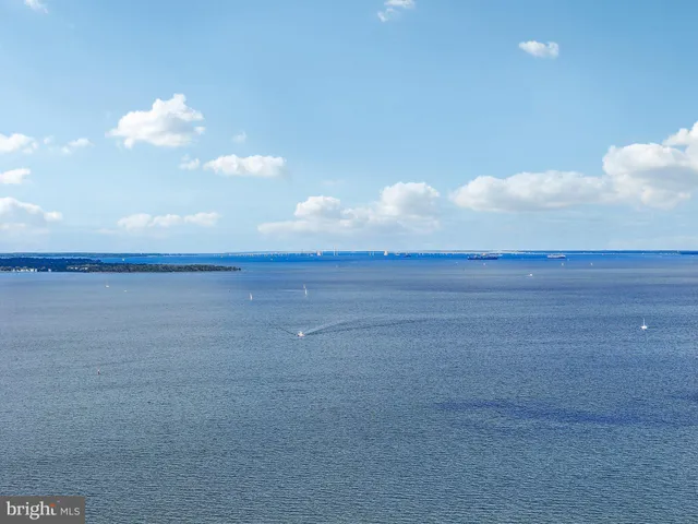 a view of a white house with a big yard plants and large trees