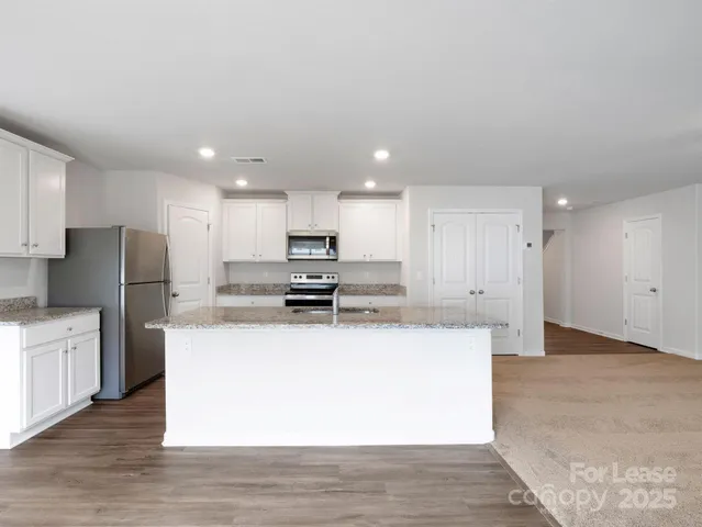 a kitchen with stainless steel appliances kitchen island sink refrigerator and cabinets