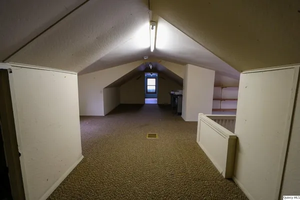 a view of a hallway to an empty room with a kitchen
