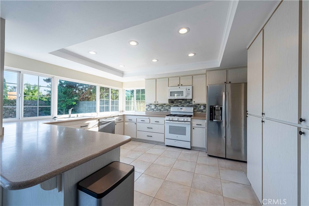 2232 Hawk Street Simi Valley, CA 93065 - Photo 12 of 39 a large white kitchen with a stove a sink dishwasher and a refrigerator with wooden floor