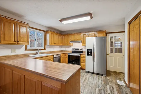 a kitchen with granite countertop a refrigerator and wooden cabinets