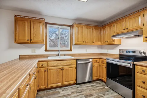 a kitchen with stainless steel appliances granite countertop a sink stove and cabinets