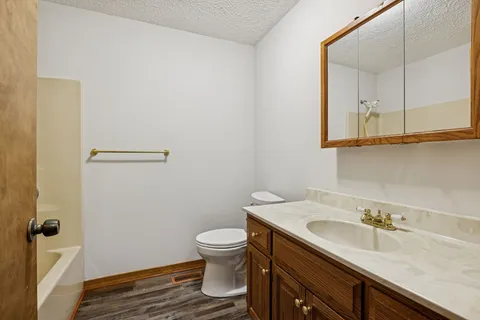 a bathroom with a granite countertop sink mirror vanity and toilet