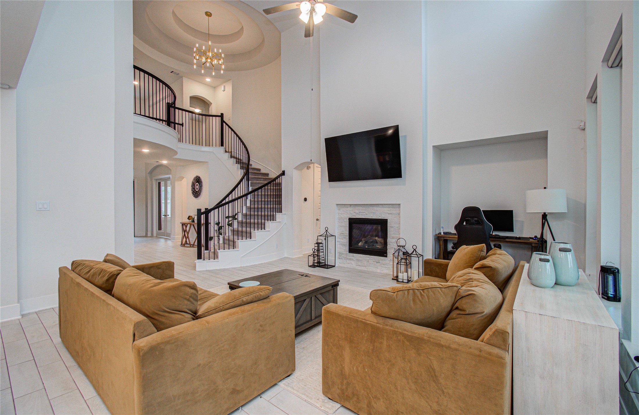 4211 Limestone Terrace Manvel, TX 77578 - Photo 11 of 33 This spacious living room features high ceilings, a modern fireplace, and a large mounted TV. The open layout includes a stylish staircase and a cozy seating area with brown sofas. A small office nook is tucked away, providing functionality and style.