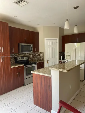a open kitchen with stainless steel appliances granite countertop a sink refrigerator and microwave