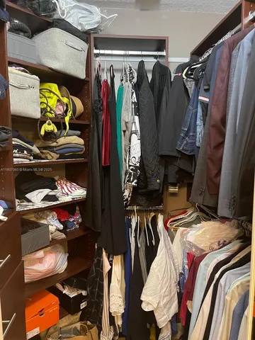 a view of walk in closet with clothes and shoes