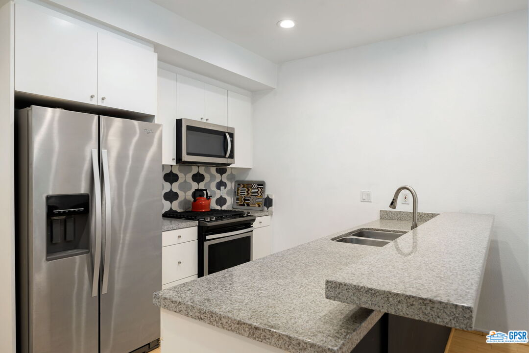 665 East Arenas Road Palm Springs, CA 92262 - Photo 14 of 40 a kitchen with granite countertop a refrigerator and a sink
