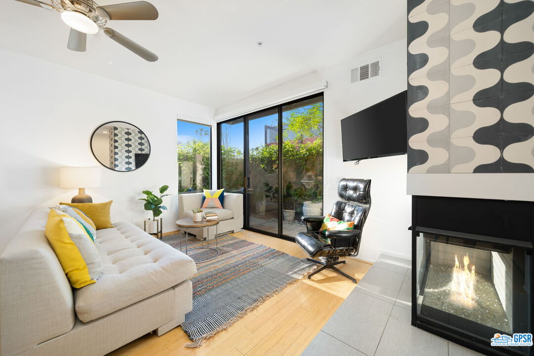 665 East Arenas Road Palm Springs, CA 92262 - Photo 7 of 40 a living room with furniture a fireplace and a floor to ceiling window