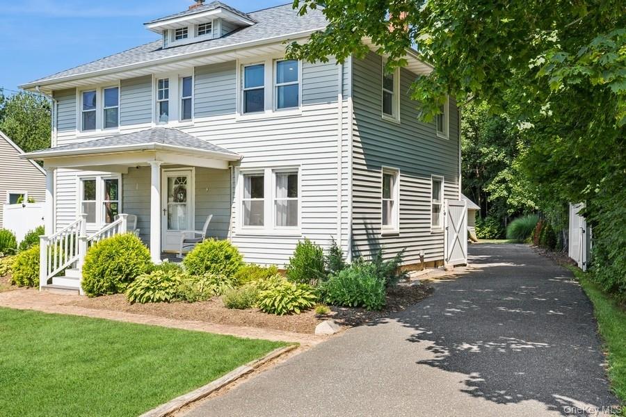 Traditional style home with roof with shingles, asphalt driveway, and covered porch