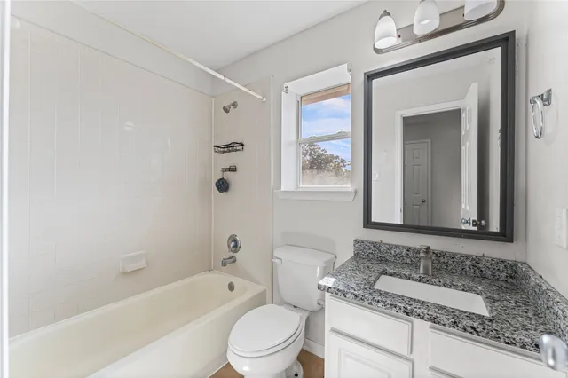 a bathroom with a granite countertop sink a toilet and shower