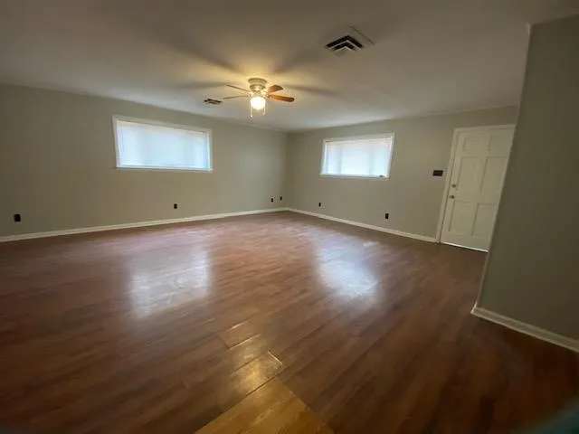 an empty room with wooden floor and windows