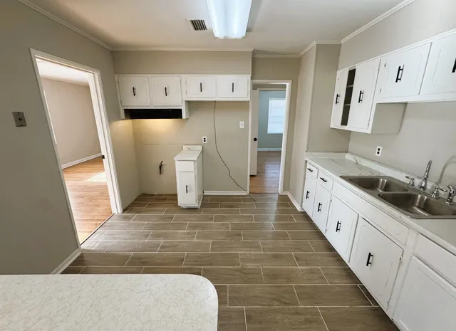 a large white kitchen with a sink and refrigerator