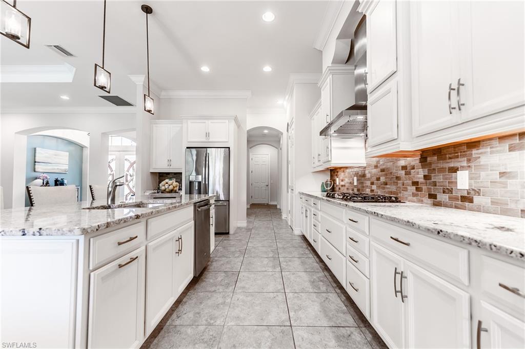 1387 Mockingbird Drive Naples, FL 34120 - Photo 15 of 46 a large kitchen with granite countertop a large white kitchen island and stainless steel appliances