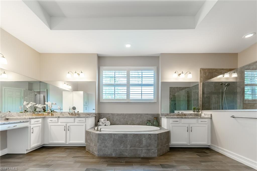 1387 Mockingbird Drive Naples, FL 34120 - Photo 23 of 46 a large white bathroom with a large tub a sink and white cabinets