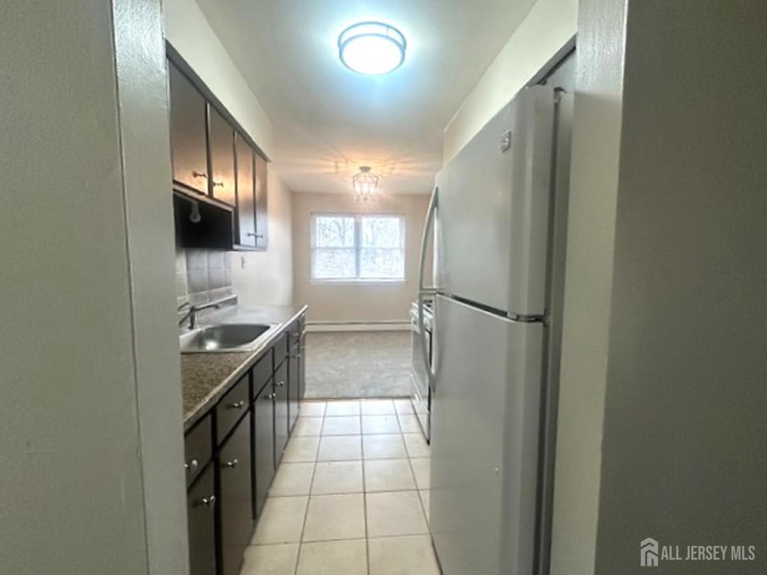 8 Manchester Court, Unit F Freehold, NJ 07728 - Photo 7 of 13 a kitchen with granite countertop a refrigerator and a sink