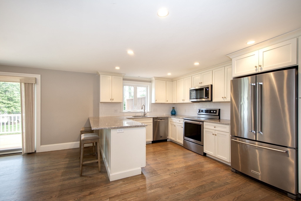 474 King Street, Unit 474 Cohasset, MA 02025 - Photo 4 of 18 a kitchen with white cabinets stainless steel appliances and wooden floor