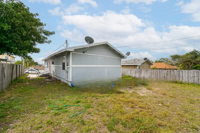 a view of backyard of house with wooden fence
