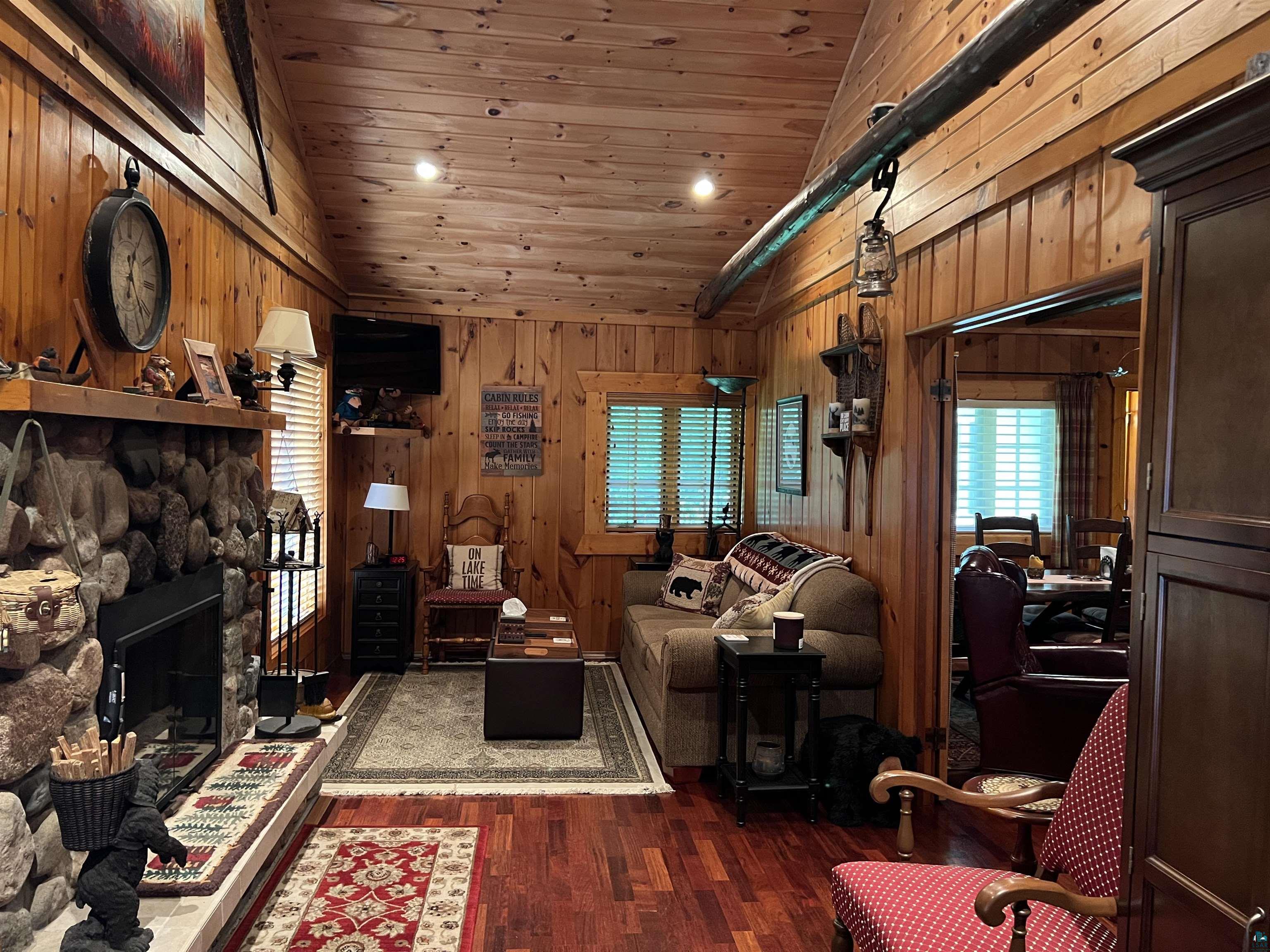 46835 Behan Drive Cable, WI 54821 - Photo 25 of 42 Living room featuring lofted ceiling, wooden ceiling, a stone fireplace, hardwood / wood-style flooring, and wood walls
