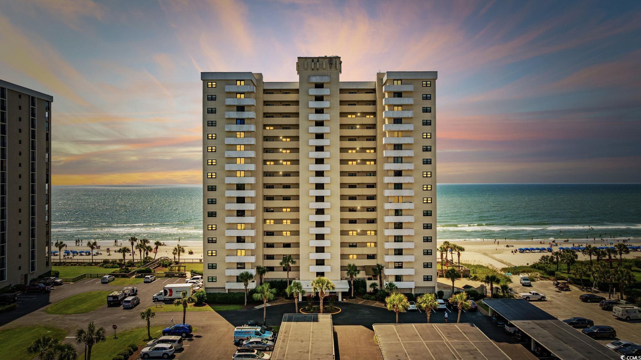 View of apartment building / complex featuring view of water and beach