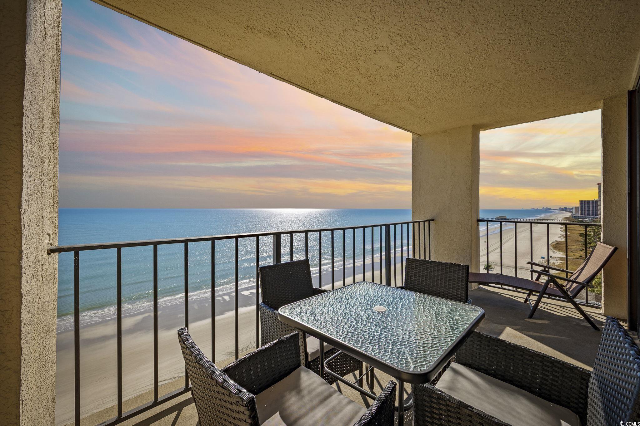 10100 Beach Club Drive, Unit 14F Myrtle Beach, SC 29572 - Photo 11 of 40 Balcony at dusk with view of water and beach and outdoor dining area